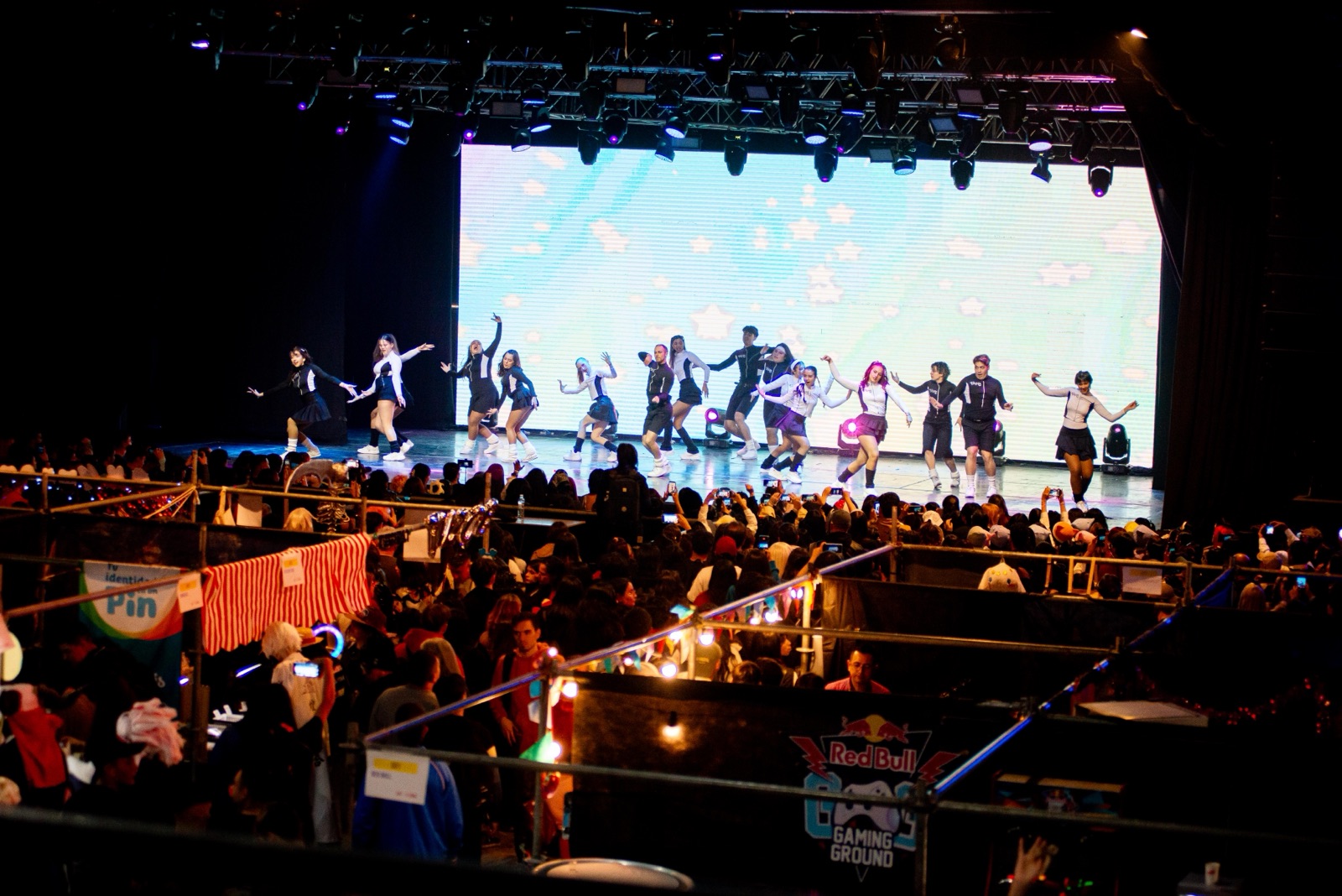 Grupo de baile K-Pop sobre el escenario, con la multitud y los stands